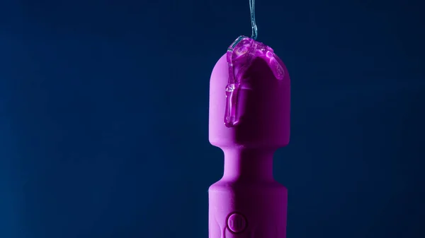 stock image Intimate lubricant pours on a purple vibrator on a blue background. Copy space