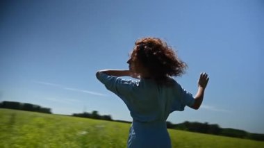 Mavi elbiseli beyaz bir kadın tarlada dans ediyor. Video 360 derece. Yavaş çekim