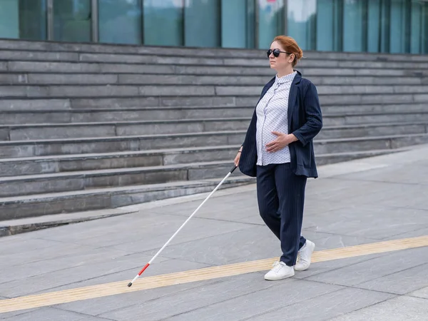 带着手杖沿着触觉瓷砖行走的盲眼怀孕女商人 — 图库照片