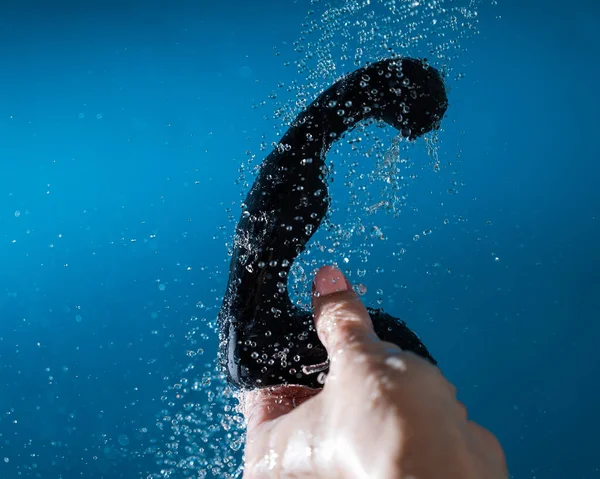 女性は青い背景の水の下で黒い前立腺刺激剤を洗う セックスおもちゃ衛生コンセプト — ストック写真