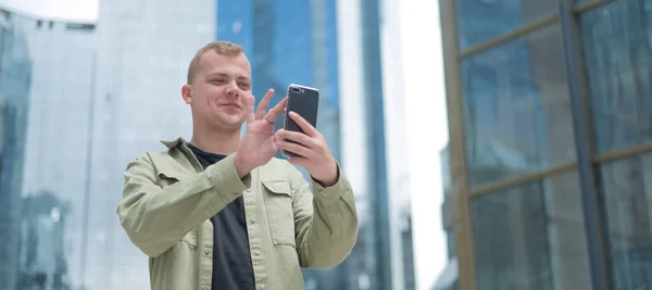 Caucasian man talking sign language over video communication on smartphone outdoors