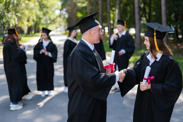 Group Graduates Robes Outdoors Elderly Man Young Woman Congratulate Each — Stock Photo, Image