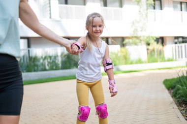 Anne kızının paten kaymasını öğrenmesine yardım ediyor.