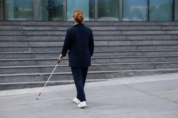 Blind businesswoman walking with tactile cane to business center