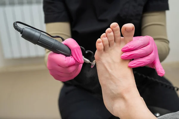 stock image A pedicurist treats the toes of a client using a machine with an abrasive disc in a beauty salon
