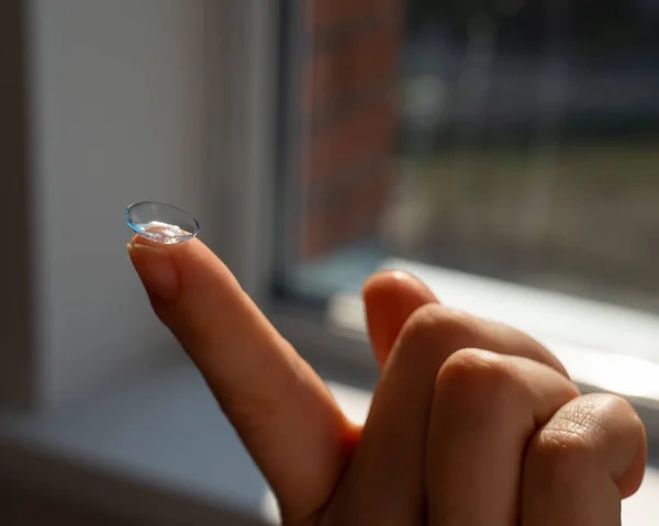 Close-up of a contact lens on a womans index finger