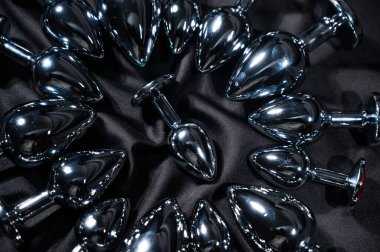 Siyah ipek bir çarşafta birçok metal anal tıkaçlar