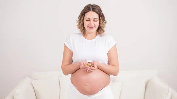 妊娠中の女性は一握りのクルミを持っている — ストック写真