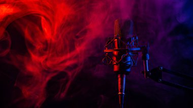 Siyah arka planda kırmızı mavi dumanlı profesyonel mikrofon.