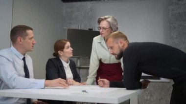 The female boss evaluates the work of subordinates. Designers engineers at a meeting