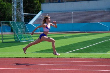 Genç beyaz kadın açık hava stadyumunda koşuya çıktı.