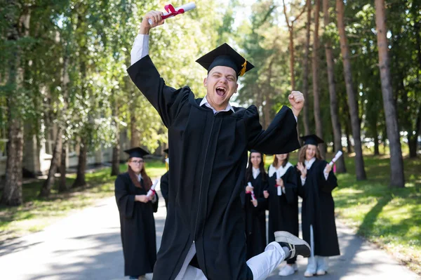 Χαρούμενος Νεαρός Καυκάσιος Που Γιορτάζει Την Αποφοίτηση Πλήθος Φοιτητών Πτυχιούχων — Φωτογραφία Αρχείου