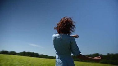 Mavi elbiseli beyaz bir kadın tarlada dans ediyor. Video 360 derece. Yavaş çekim