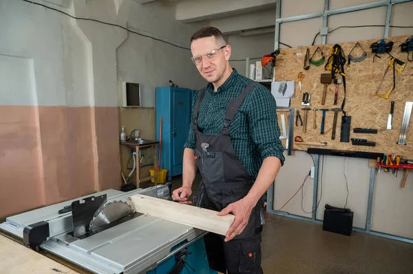 stock image The carpenter cuts a wooden board on a circular machine