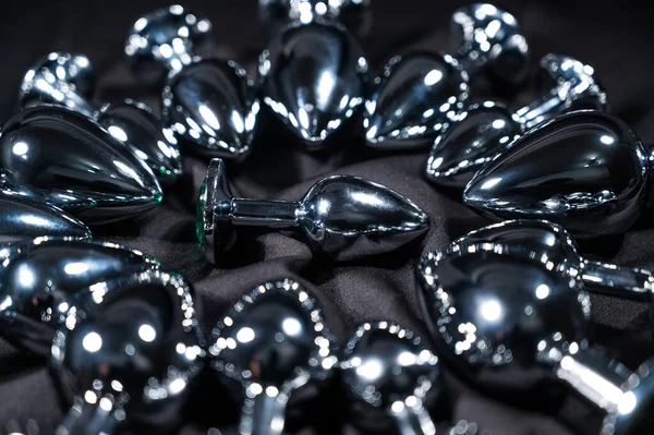 ブラックシルクシート上の多くの金属アナルプラグ — ストック写真