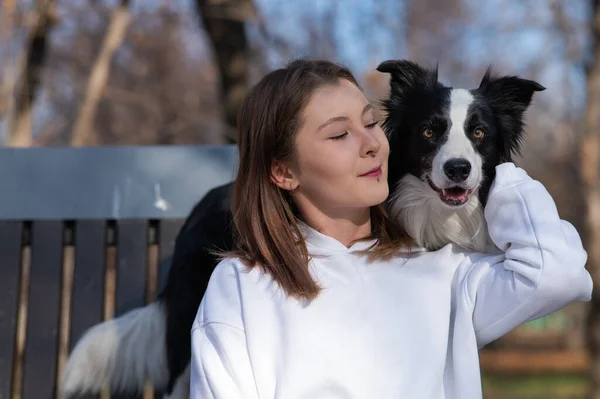 白人女性抱擁彼女の犬ボーダーコリーながら 秋の公園のベンチに座って — ストック写真