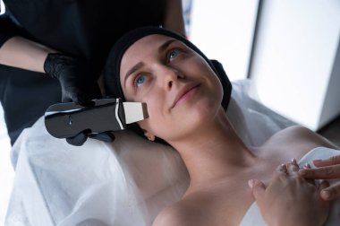 Ultrasonik temizlik prosedürü uygulayan bir kadın. Donanım kozmetolojisi