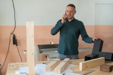 Atölyede telefonla konuşan beyaz bir adamın portresi.