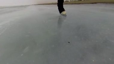 Donmuş bir gölde buz pateni yapan bir artistik patinajcının bacaklarının yakın çekimi.