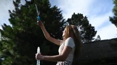 Mutlu beyaz kadın doğada sabun köpüğü üflüyor. Video 360 derece