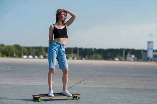 stock image Young caucasian woman riding a longboard outdoors