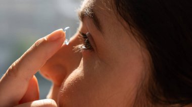 Close-up portrait caucasian woman putting on a contact lens