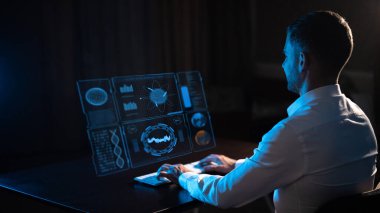 Caucasian man sitting in the dark in front of a virtual menu and typing on a keyboard