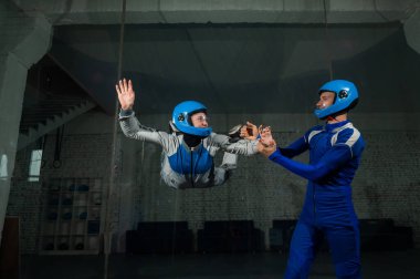 Erkek bir eğitmen bir kadına rüzgar tünelinde uçmayı öğretir. Serbest düşüş simülatörü