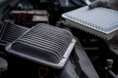 Araba motorundaki hava filtresini değiştiriyor.