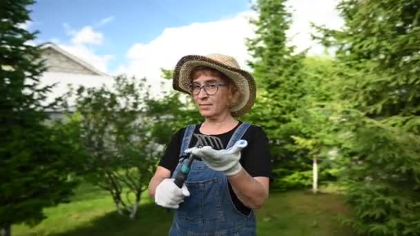 一个戴着帽子和工作服的老年妇女的画像是拿着一个园艺工具 视频360度 — 图库视频影像