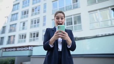 Video 360 derece. Kafkasyalı iş kadını akıllı telefona bakıyor ve dışarıda gülmeye başlıyor.