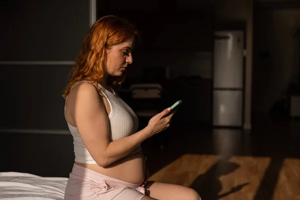 Una Mujer Embarazada Usa Teléfono Inteligente Mientras Está Sentada Cama —  Fotos de Stock
