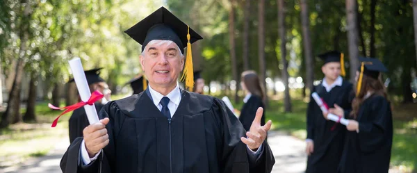 Group Graduates Robes Outdoors Elderly Student Rejoices Receiving Diploma Widescreen — Stock Photo, Image