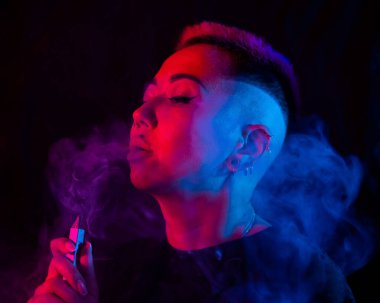 Tıraşlı şakakları olan Asyalı bir kadın neon ışıkta sigara içiyor.