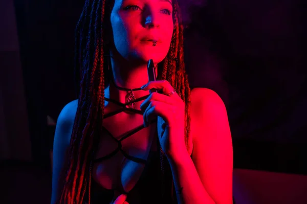 Caucasian Girl Dreadlocks Smokes Vape Red Blue Light — Stock Photo, Image