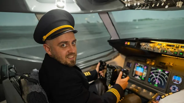 Uçuş simülatöründe otururken gülümseyen beyaz sakallı adam. Pilot kokpitte.