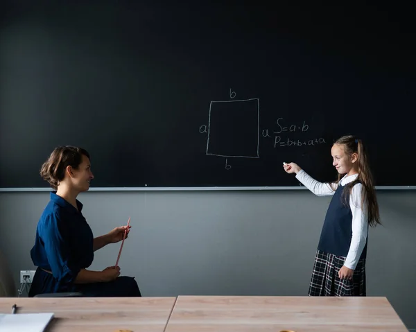 Blank Klein Meisje Beantwoordt Vraag Van Vrouwelijke Leraar Het Schoolbord — Stockfoto