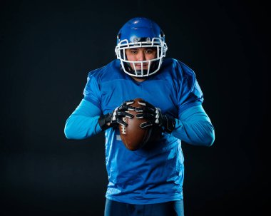 Siyah arka planda Amerikan futbolu için mavi üniformalı bir adamın portresi.