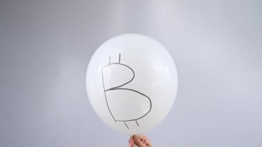 Bir kadın, yazıt bitcoin ile bir balonu iğneyle deliyor. Kripto para birimi düşüş metaforu