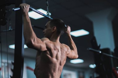 A man does a chest pulldown in the gym
