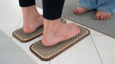 Kafkasyalı kadın terapist desteğiyle sadhu tahtasında duruyor.