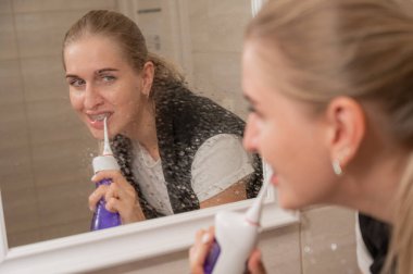 Dişlerinde diş teli olan bir kadın sulayıcı kullanır. Yakın plan portre