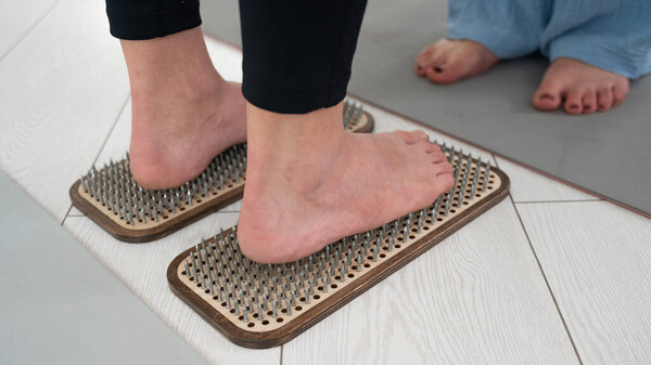 Кавказка стоит на досках садху при поддержке терапевта