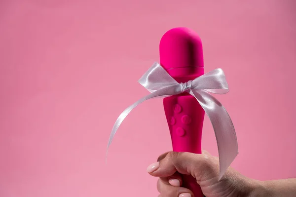 stock image Woman holding pink vibrator with white bow on pink background. Copy space