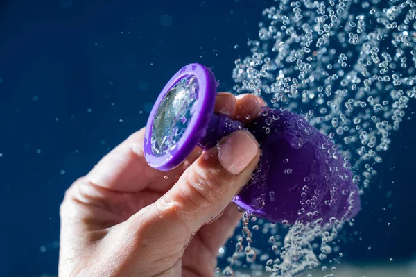 stock image Woman washing purple anal plug under shower on blue background