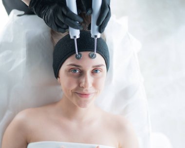 Genç beyaz kadın mikro akım terapi prosedürü uyguluyor. Güzellik bürosu