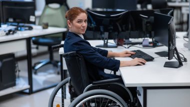 Caucasian smiling woman in wheelchair at work desk