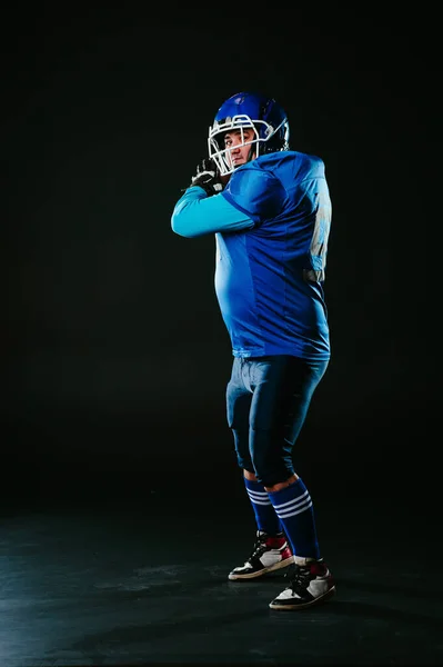 Портрет Человека Синей Форме Американского Футбола Бросает Мяч Черном Фоне — стоковое фото