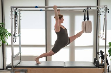 Hamile bir kadın bir reformcu üzerinde pilates yapıyor. Hava jimnastiği