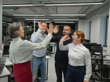 Four co-workers give a high five in the office